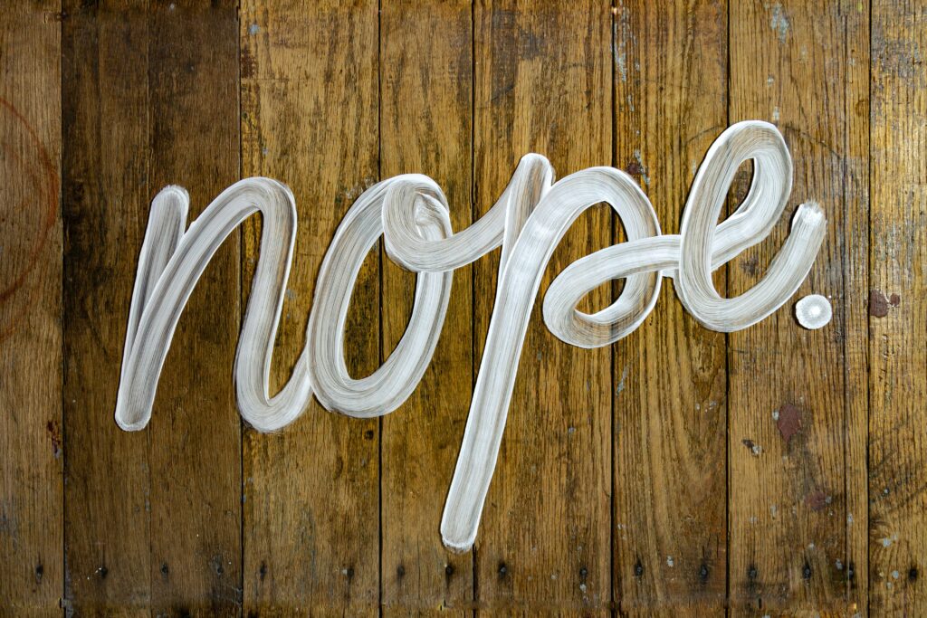 the word nope painted in white on a wooden background
