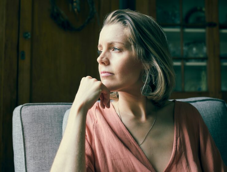 Woman sitting thoughtfully, looking out of a window